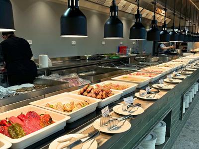 Buffet mit warmen Speisen in einem modernen Hotelrestaurant mit Lampen und Geschirr.