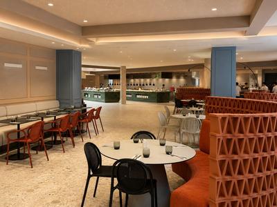 Großer Hotelinnenraum mit Tischen, Stühlen und einer Restauranttheke im Hintergrund.