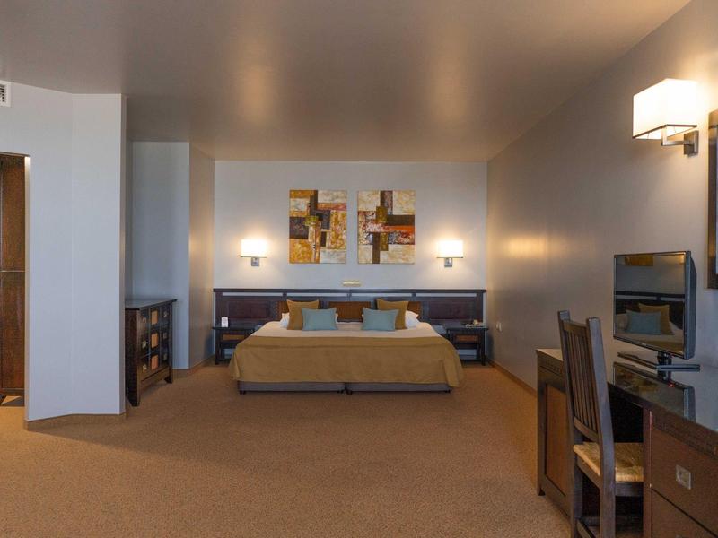 Habitación de hotel moderna con cama grande, escritorio y luz cálida de lámparas.