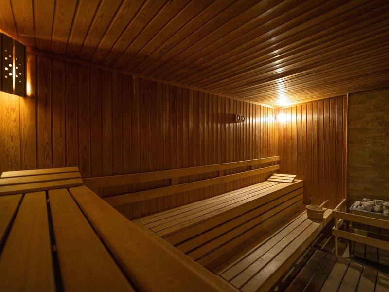 Interior de sauna con bancos de madera y luces cálidas, ambiente acogedor para relajación.