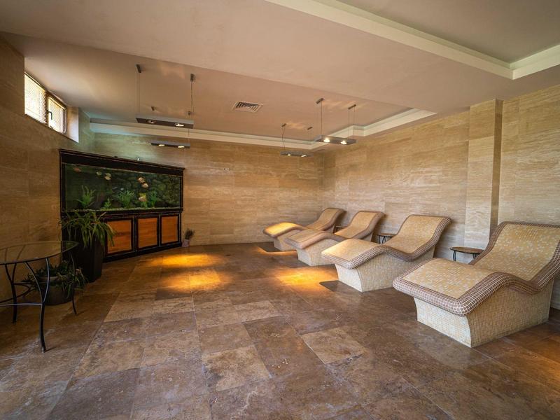 Sala de relajación con tumbonas claras y acuario, paredes y suelo de piedra natural en tonos cálidos.