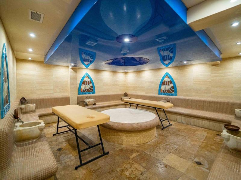 Sala de descanso de spa moderna con camillas de masaje y tanque de agua central en ambiente cálido.