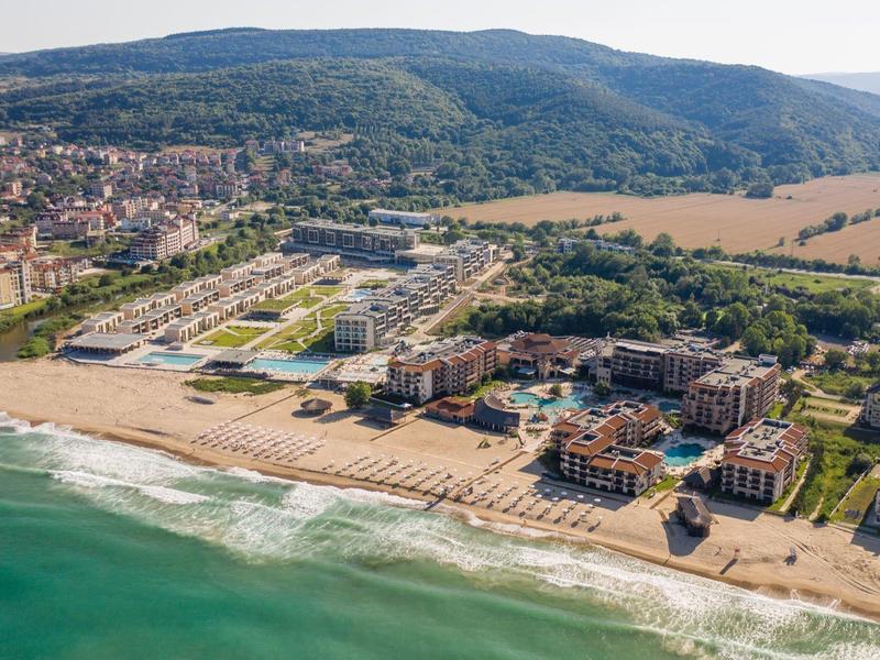 Vista aérea de un hotel en la playa con paisaje y ciudad circundantes.