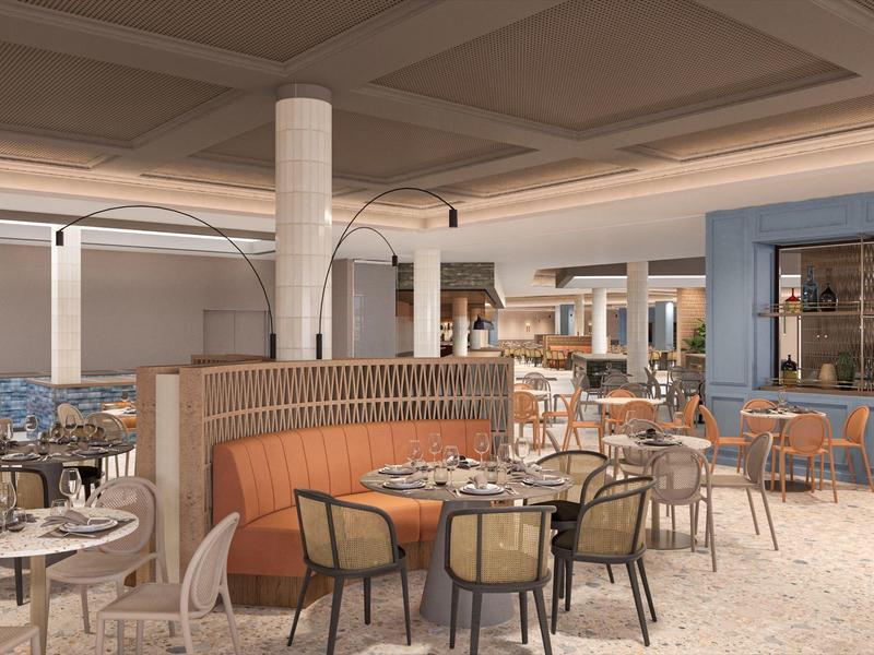 Interior moderno de restaurante con asientos acolchados y mesas elegantemente preparadas en colores cálidos.