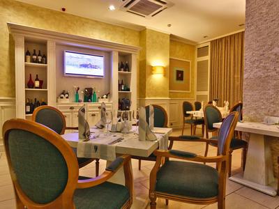 Elegantes Restaurant mit gedeckten Tischen und klassischen Stühlen in warmem Licht.