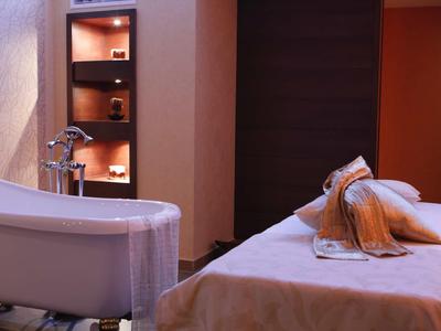 Gemütlicher Wellnessraum mit Badewanne, Massageliege, warmem Licht und weichen Handtüchern.