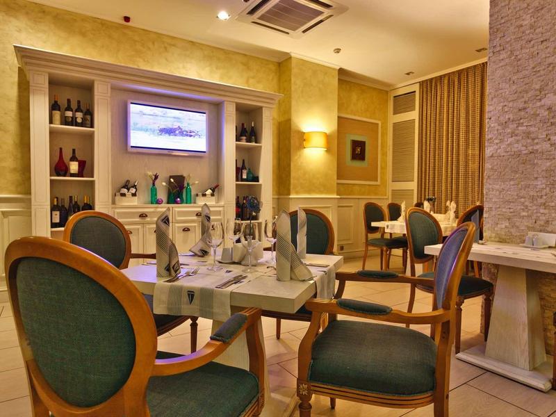 Elegantes Restaurant mit grünen Stühlen, Deckentuchlampen und warmen Beigetönen an Wänden.