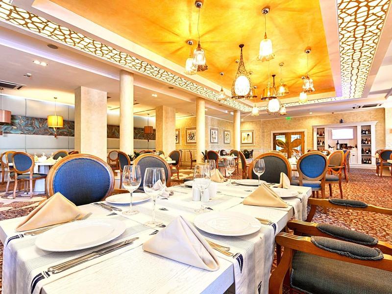 Elegantes Restaurant mit gedeckten Tischen, blauen Stühlen und warmem, hellem Licht.