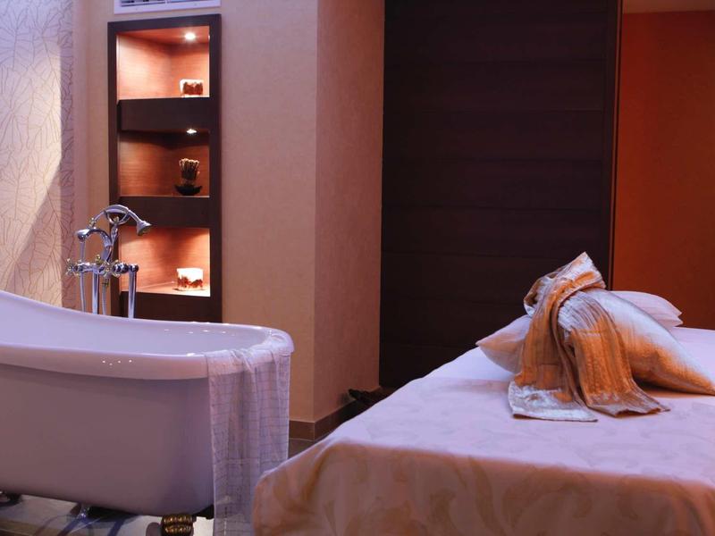 Gemütlicher Wellnessraum mit Badewanne, Massageliege, warmem Licht und weichen Handtüchern.