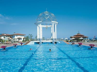 Blick auf einen großen Außenpool mit einem weißen Pavillon in tropischer Resortumgebung.