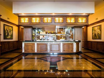 Área elegante de bar de hotel con revestimiento de madera, suelo de baldosas y barra iluminada.