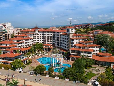Vista de un complejo con techos rojos y una gran piscina bajo un cielo azul.