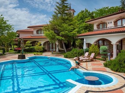 Elegante Hotelanlage mit großem Pool, Liegestühlen und grünen Bäumen zu sehen.