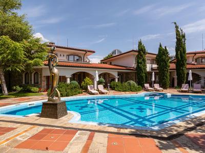 Hotelpool mit Liegestühlen und Statuen unter blauem Himmel