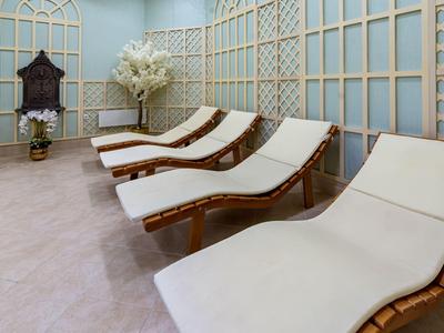 Cuatro cómodas tumbonas con cojines blancos en una sala de descanso luminosa con paredes decorativas de madera.