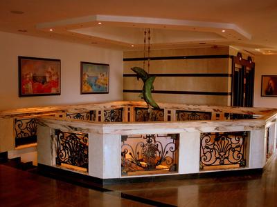 Elegante Rezeption mit dekorativem Geländer und moderner Skulptur in einem Hotel.