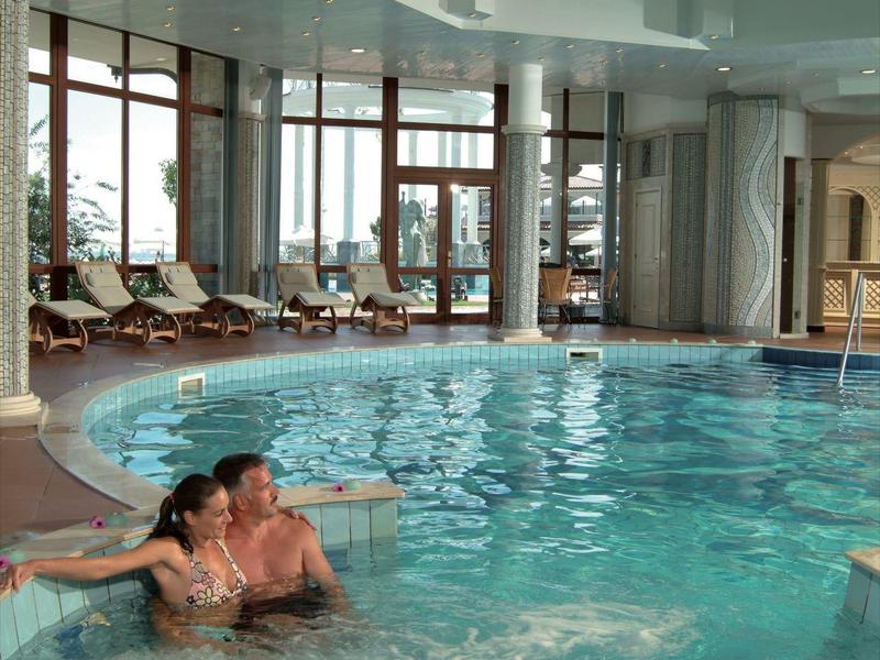 Piscina interior con jacuzzi, sillas reclinables y ventanas grandes que ofrecen luz natural.