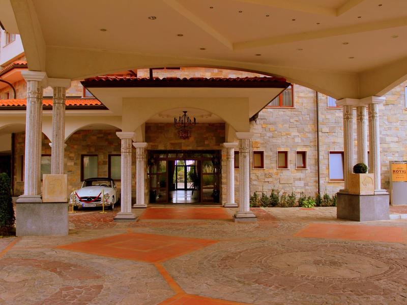 Entrada de un hotel con pórtico cubierto y columnas de piedra y madera.