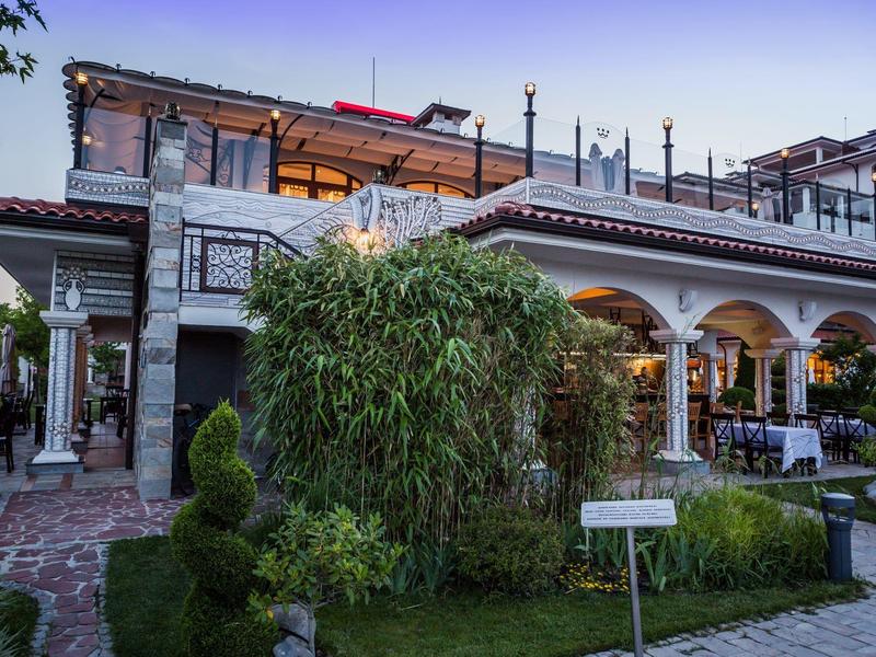 Edificio moderno de hotel con árboles y jardín cuidado bajo cielo despejado.