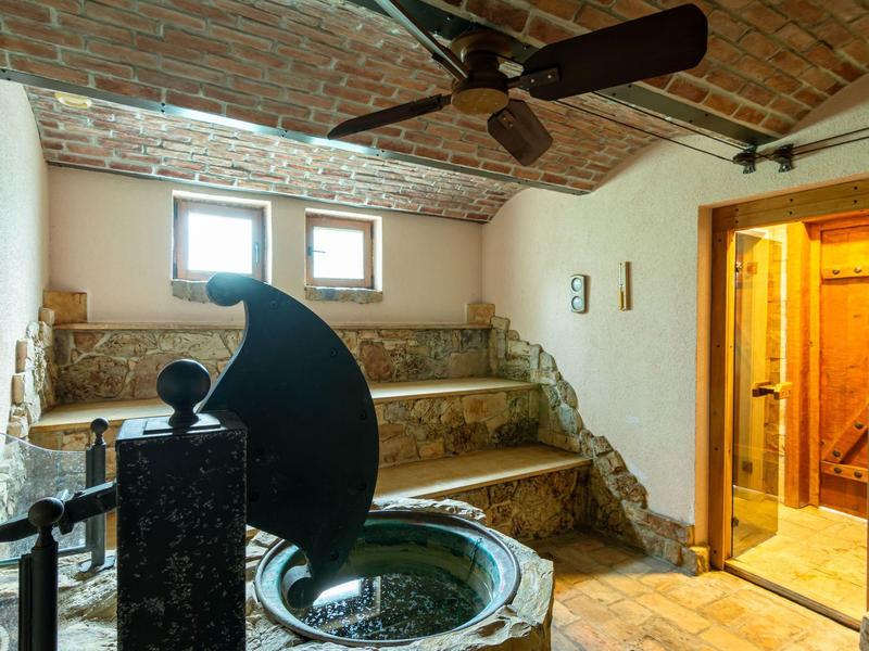Sala de bienestar acogedora con sauna, jacuzzi y bancos de mampostería bajo un techo abovedado.