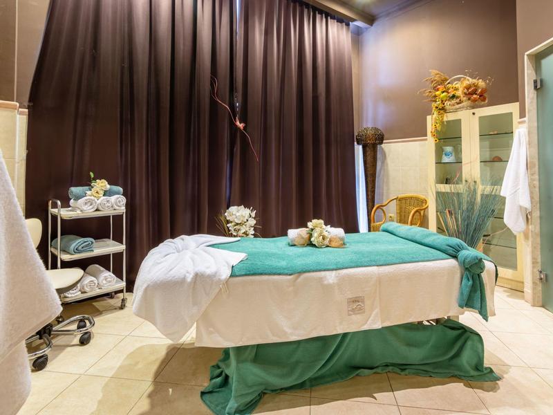 Sala de masaje acogedora con camilla, luz suave y elementos decorativos.