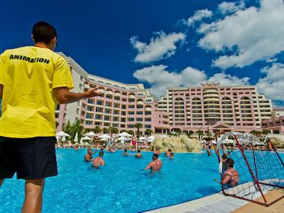 Rettungsschwimmer überwacht Schwimmer in einem großen Hotelpool unter blauem Himmel.