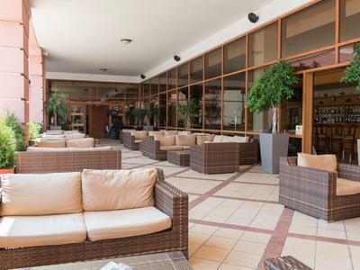 Cozy wicker seating on a covered hotel terrace with plants.