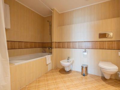 Helles Hotelbadezimmer mit Badewanne, WC, Bidet und braunen Fliesen.