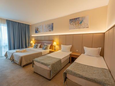 Hotelzimmer mit zwei Einzelbetten, einem Doppelbett und weichen, warmen Farben.