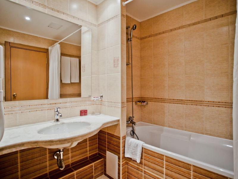 Modern bathroom with sink, large mirror, and bathtub with shower fixture.