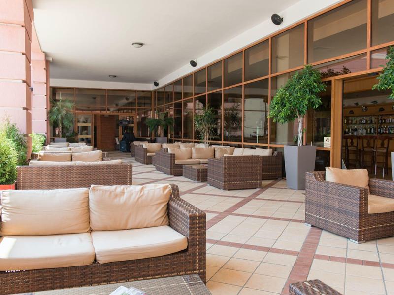 Cozy wicker seating on a covered hotel terrace with plants.