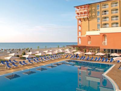 Hotel pool with blue loungers and sea view under clear sky