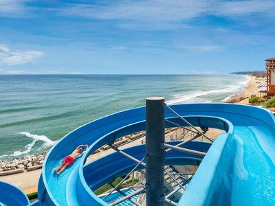 Große blaue Wasserrutsche mit Meerblick an einem Strandresort.