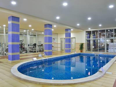 Indoor pool area with fitness equipment and large windows in a hotel.