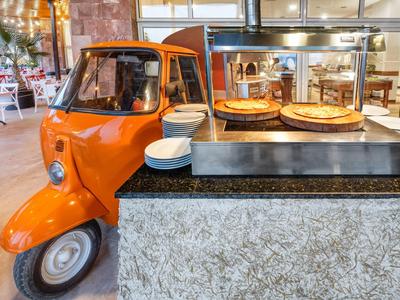Orange tuk-tuk next to a buffet with cakes in a restaurant