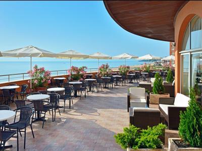 Terrace with tables, chairs, and umbrellas overlooking the sea.
