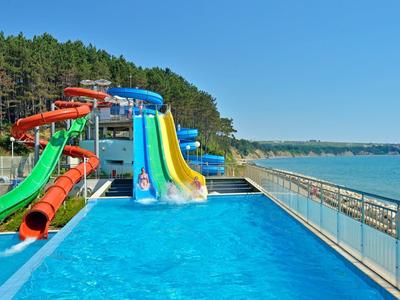 Water park with colorful water slides next to a pool and sea view