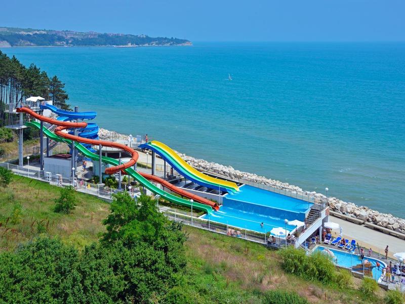 Several colorful water slides along the coast overlooking the blue sea.