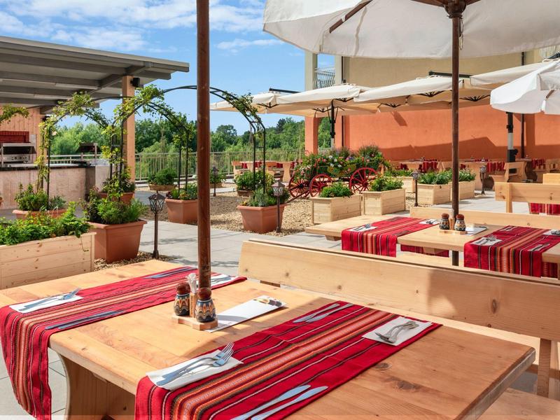 Cozy outdoor seating with wooden benches and tables, decorated with red runners and umbrellas.