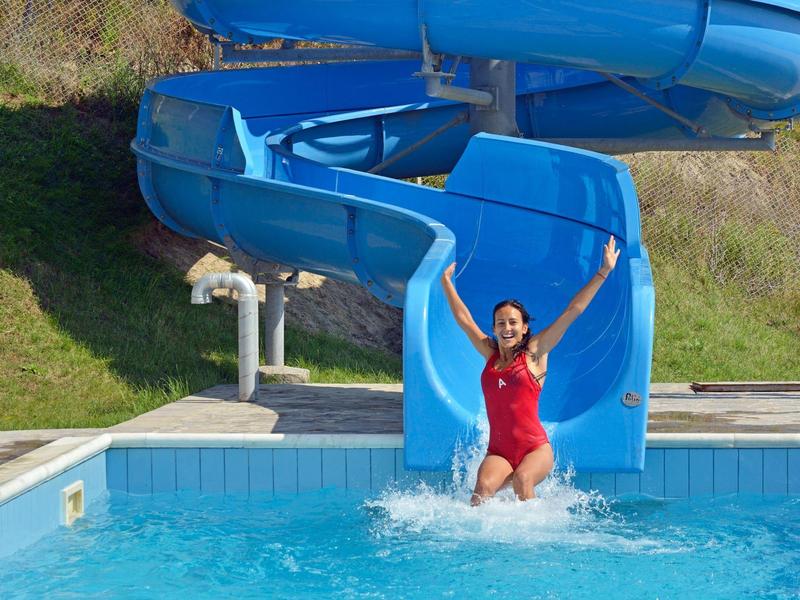 Woman in red swimsuit slides down water slide into swimming pool