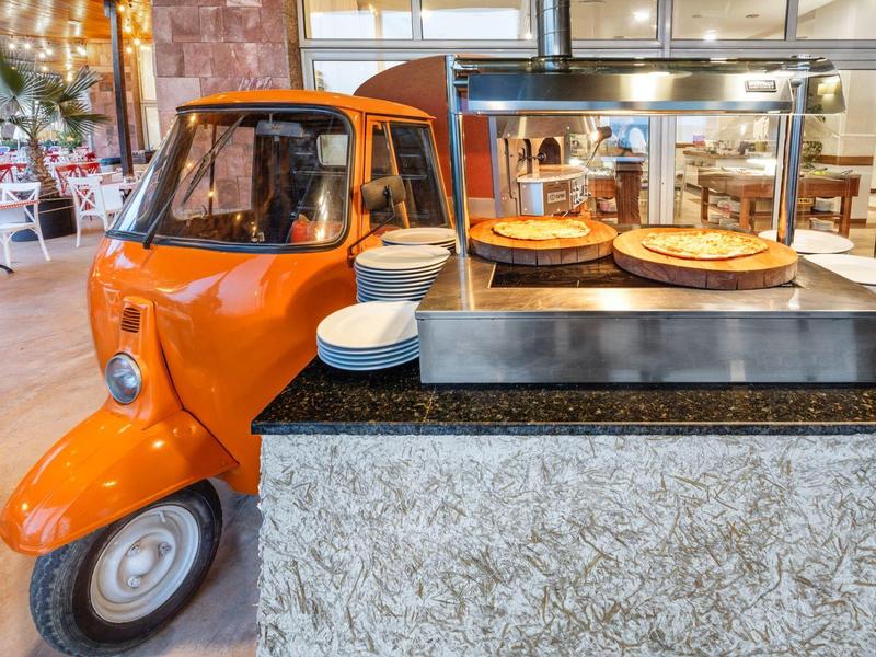 Orange tuk-tuk next to a buffet with cakes in a restaurant