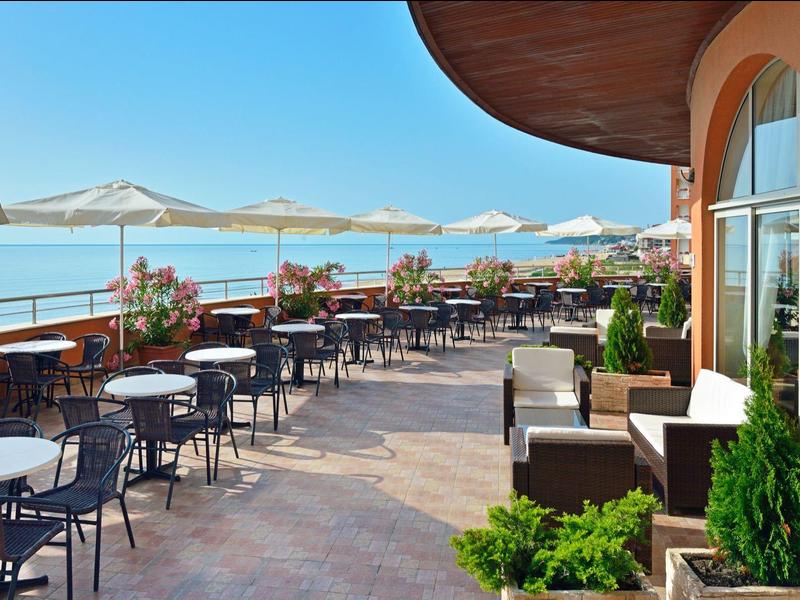 Terrace with tables, chairs, and umbrellas overlooking the sea.