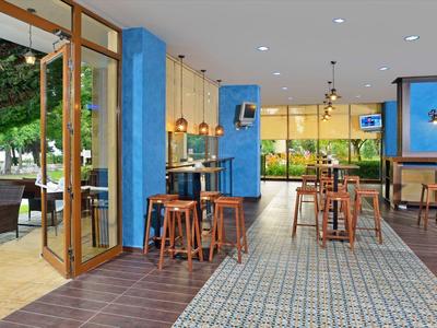 Moderner Caféinnenraum mit blauen Wänden, Holzmöbeln und offenem Zugang zu Terrasse mit Garten.