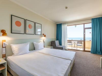 Modernes Hotelzimmer mit zwei Betten und Balkon mit Meerblick.