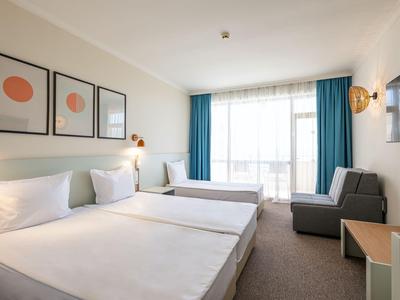 Helles Hotelzimmer mit zwei Einzelbetten, großem Fenster und schlicht dekoriert.
