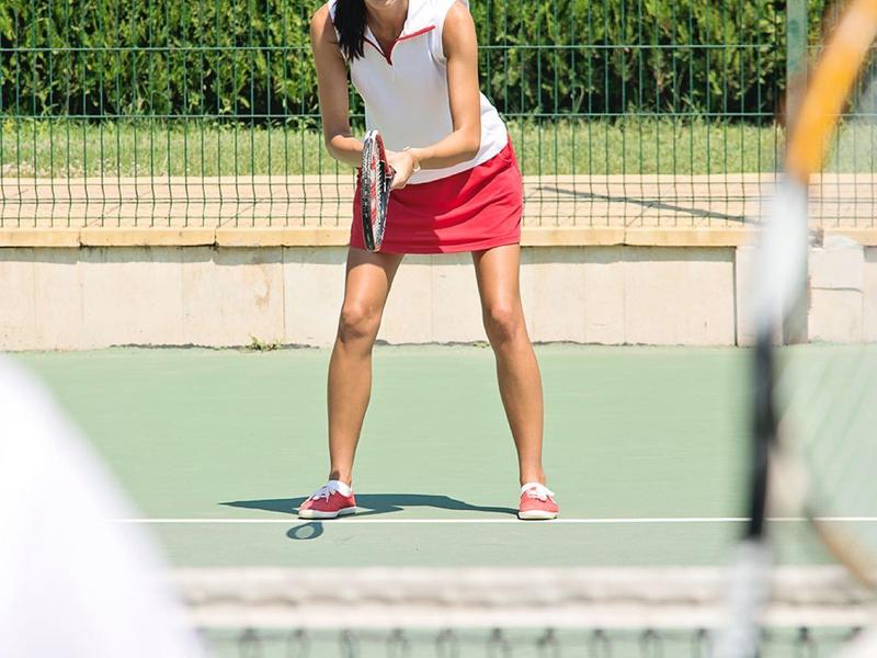 Donna in abbigliamento sportivo che si prepara a servire sul campo da tennis.