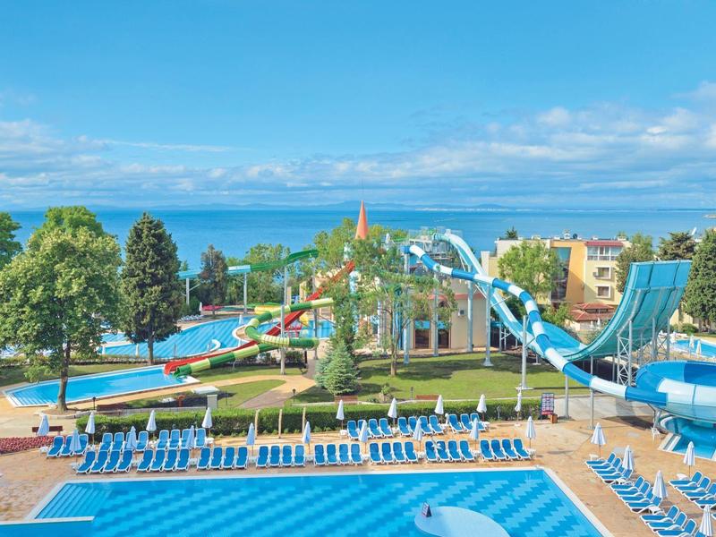 Grande piscina all'aperto con scivoli d'acqua e sedie a sdraio, vista sul mare e cielo azzurro