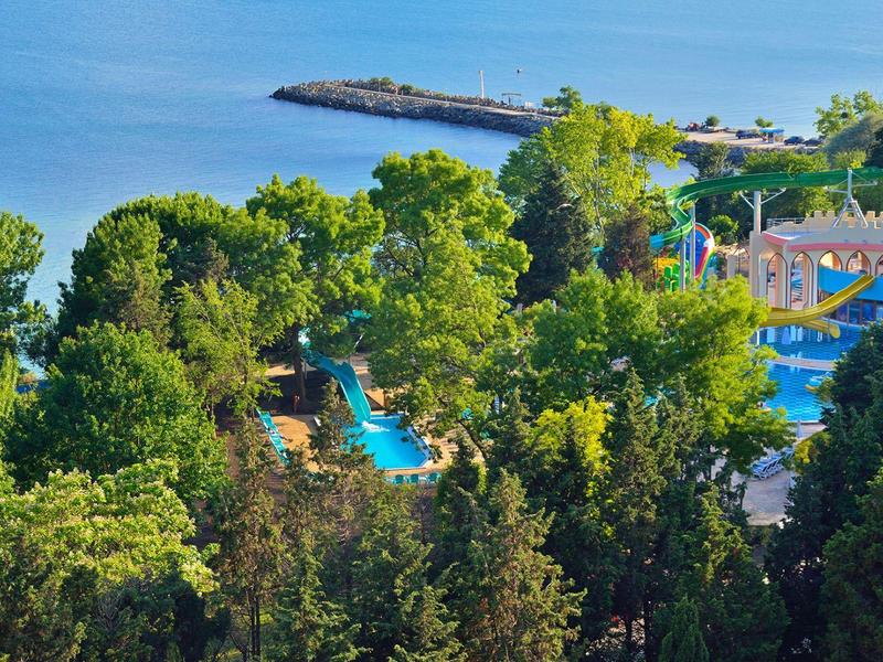 Hotel con grande piscina circondato da alberi verdi vicino al mare.