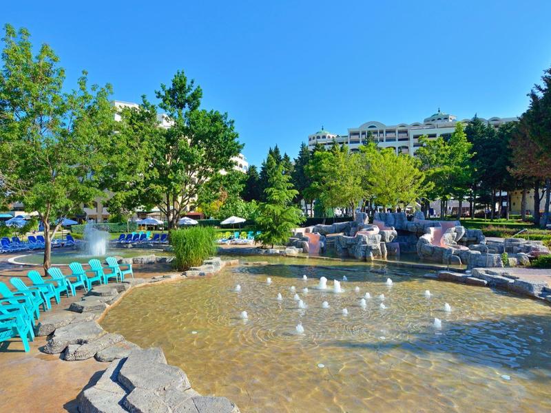 Vista di uno stagno tranquillo in un parco con sedili e alberi sotto un sole splendente