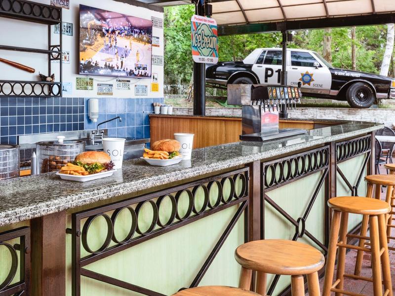 Bar accogliente con sgabelli di legno e un'auto della polizia come decorazione sullo sfondo.